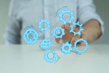 Stock photo of a person's hand interacting with digital gears, symbolizing teamwork, collaboration, and workflow.