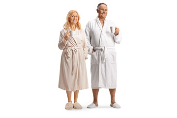 Mature man and woman in bathrobes holding cups