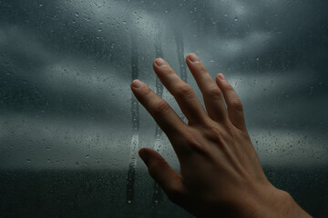 Frosted window with dragging condensation reveals stormy sky creating gloomy mood and textured atmosphere