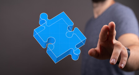 Person reaching towards a blue puzzle piece representing teamwork, connection and solving a...