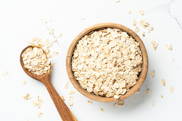 Rolled oats or oat flakes in a wooden bowl on white background.