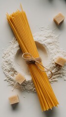 Raw spaghetti, flour and sugar cubes on white background, top view