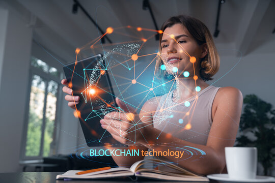 Woman using tablet with futuristic blockchain technology interface concept in modern office environment with digital network overlay.