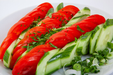 Fresh Sliced Tomatoes and Cucumbers with Green Onions and Herbs on a White Plate. Healthy Summer Salad, Vegan Food, Organic Vegetables, Clean Eating Concept