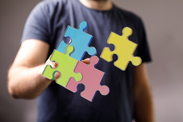 A person's hand arranging colorful jigsaw puzzle pieces, symbolizing teamwork, problem-solving, connection, and completion. Perfect for business