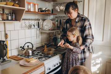 Mother teaching daughter cooking skills in kitchen