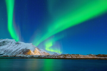 Aurora Borealis in Scandinavia. Norway, Lofoten islands. Northern lights over the mountains. Starry sky. Winter landscape on the north. Photo for background, wallpaper, postcards.
