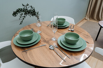 An exquisite and stylish modern dining table setup featuring beautifully arranged green dishware, elegant cutlery, and chic decor elements to create a vibrant atmosphere for meals