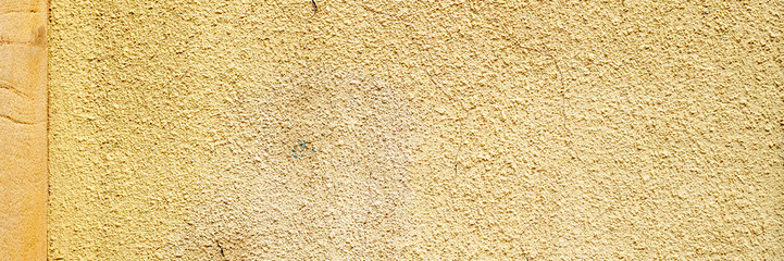 Old painted yellow cement wall. Rough building surface. Colorful grunge background