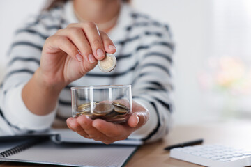 Woman putting money into jar at wooden table indoors, closeup