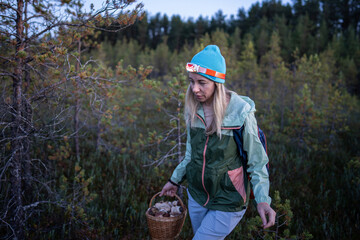 Female hiker searching for wild mushrooms in dim woodland using forehead light on fall season. Fungi hunting in evening, foraging autumn harvest in forest, solo explorer, cold weather gathering