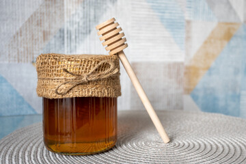 Fototapeta premium Glass bowl of natural honey and wood spoon on the table.