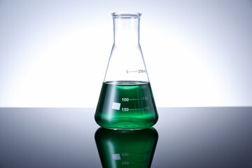 Flask with green liquid on table against white background