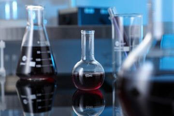 Different glassware with red liquid on table in laboratory, selective focus