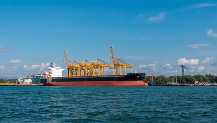 Fototapeta premium Container Ship at Port with Cranes and Blue Sky Above