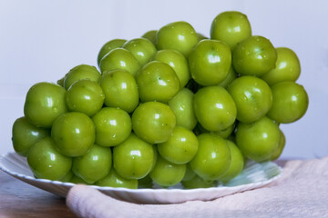 Large green Korean grapes on flat plate on light background.