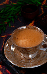 Black coffee with foam in a brown ceramic cup on a dark background
