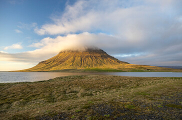 clouds cover the the peak of Mount Kirkjufell in the evening lights, Snaefellsnes Peninsula, West Iceland