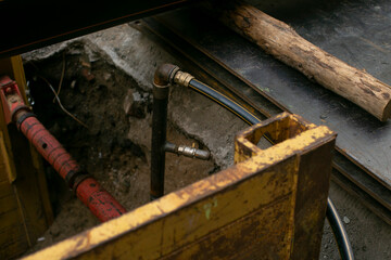An excavation area that contains pipes, hoses, and a log positioned near various construction equipment