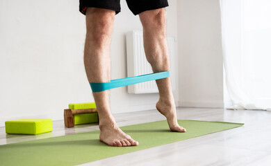 Sporty Man Doing Sport Exercises With Resistance Rubber Band At Home
