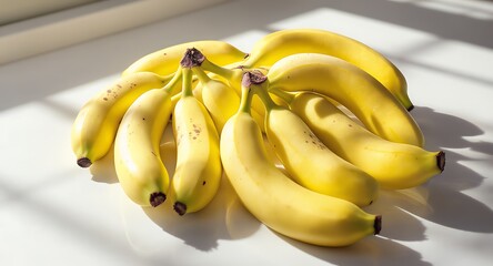 Bunch of ripe yellow bananas on white surface with sunlight and shadow
