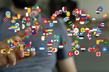 Concept of international relations. Person's hand points at a cluster of country flags, representing connection, diplomacy, and world citizenshi