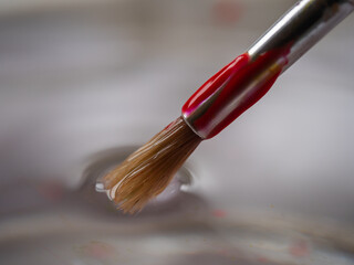 Cleaning water color paint brushes in jar of water