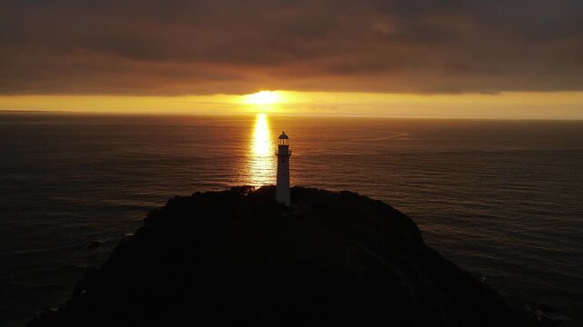 Vista a&eacute;rea com drone do far&oacute;l da conchas da Ilha do Mel em Paranagu&aacute; no litoral do Paran&aacute; com oceano atl&acirc;ntico e c&eacute;u nublado ao fundo ao nascer do sol alaranjado