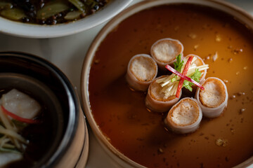 Delicate dim sum rolls, shrimp or pork, are beautifully plated in a rich, savory brown sauce. The six rolls are garnished with thin slices of ginger and a sliver of red chili. 