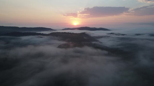 Vista a&eacute;rea com voo de drone ao nascer do sol em Morretes no litoral do Paran&aacute; sobre a mata atl&acirc;ntica com vista para montanhas sob neblina com raios de sol