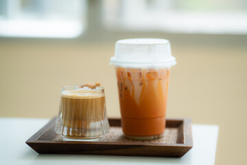 Close up glass of ice thai tea, dirty coffee on wooden table of a coffee shop summer terrace, menu photography.