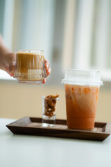 hand of woman holding a glass of dirty coffee on white table 
