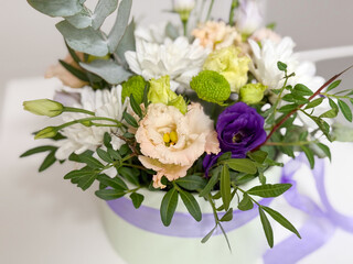 Floral arrangement with roses, chrysanthemums and lisianthus in round gift box tied with lilac ribbon. Celebration bouquet, romantic decoration, elegance, tenderness, festivity, interior beauty and