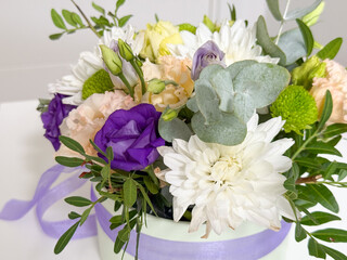 Floral arrangement with roses, chrysanthemums and lisianthus in round gift box tied with lilac ribbon. Celebration bouquet, romantic decoration, elegance, tenderness, festivity, interior beauty and