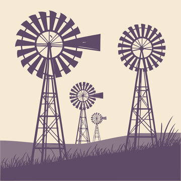 Vintage windmills silhouetted against a creamy sky on a grassy hillside