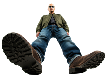 Bald man in bomber jacket and jeans isolated, looking down from a low angle, with large boots, fashion and style concept