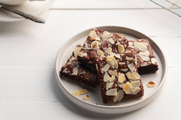 Crispy baked fudge almond brownies.Chocolate Brownie with Almond Sliced Topping in white plate.