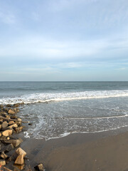The evening sun sets over Tharangambadi beach in Tamil Nadu, across the calm waters of the Bay of Bengal along this peaceful shoreline.
