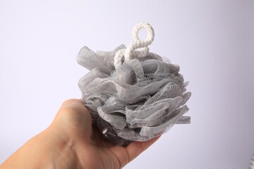 Woman holding grey mesh sponge on white background, closeup