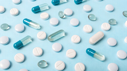 Assorted blue and white medical pills and capsules scattered on pastel background symbolizing healthcare pharmacy innovation and modern medicine concept