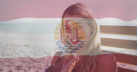 Relaxing woman wearing red bikini sitting on wooden lounge chair at beach, with emblem flag overlay