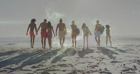 Fototapeta premium Walking group of eight surfers in swimwear carrying surfboards toward ocean at beach, wet sand