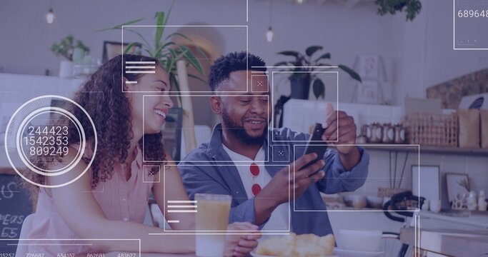 Pointing couple showing smartphone screen at coffee counter, with orange juice, cup and croissants