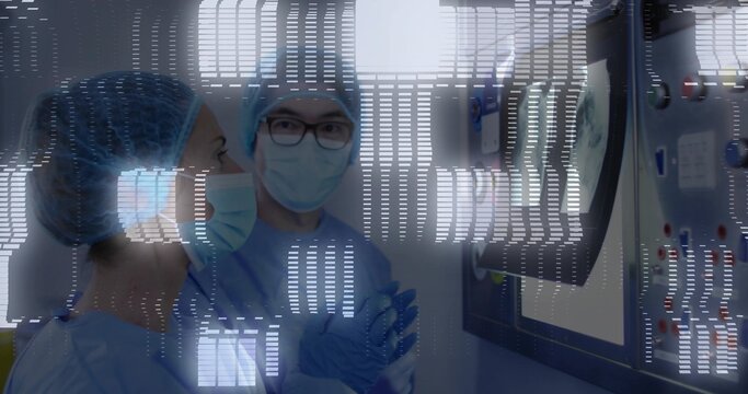 Observing two surgeons in scrubs monitoring data in operating room with wall monitor, control panel - Powered by Adobe