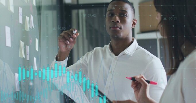 Man in white button-down shirt annotating glass board in office, with sticky notes and graphs - Powered by Adobe