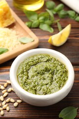 Fresh pesto sauce and ingredients on wooden table, closeup