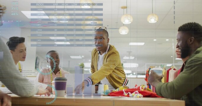 Collaborating six designers leaning over wooden worktable in studio, with swatches, tape measures - Powered by Adobe