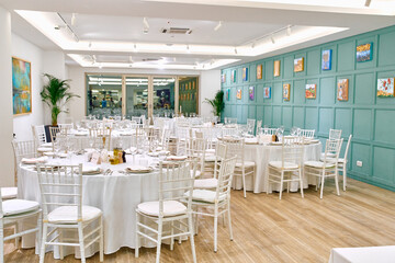 Elegant Dining Setting with Round Tables and White Chairs in a Tastefully Decorated Restaurant Featuring Green Walls and Colorful Artwork