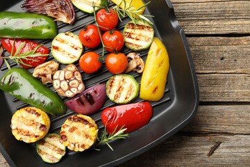 Pan with grilled vegetables and spices on wooden table, top view