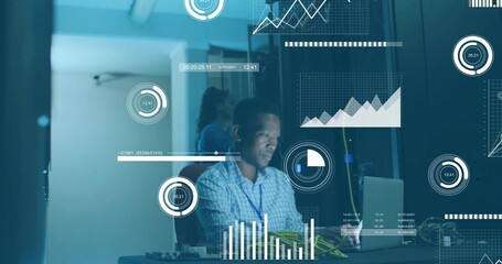 Mid adult man wearing blue shirt monitoring data charts in server room, with laptop, server rack